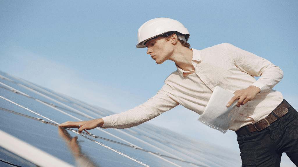 Tecnico con foglio in mano e caschetto protettivo che controlla impianto fotovoltaico. 